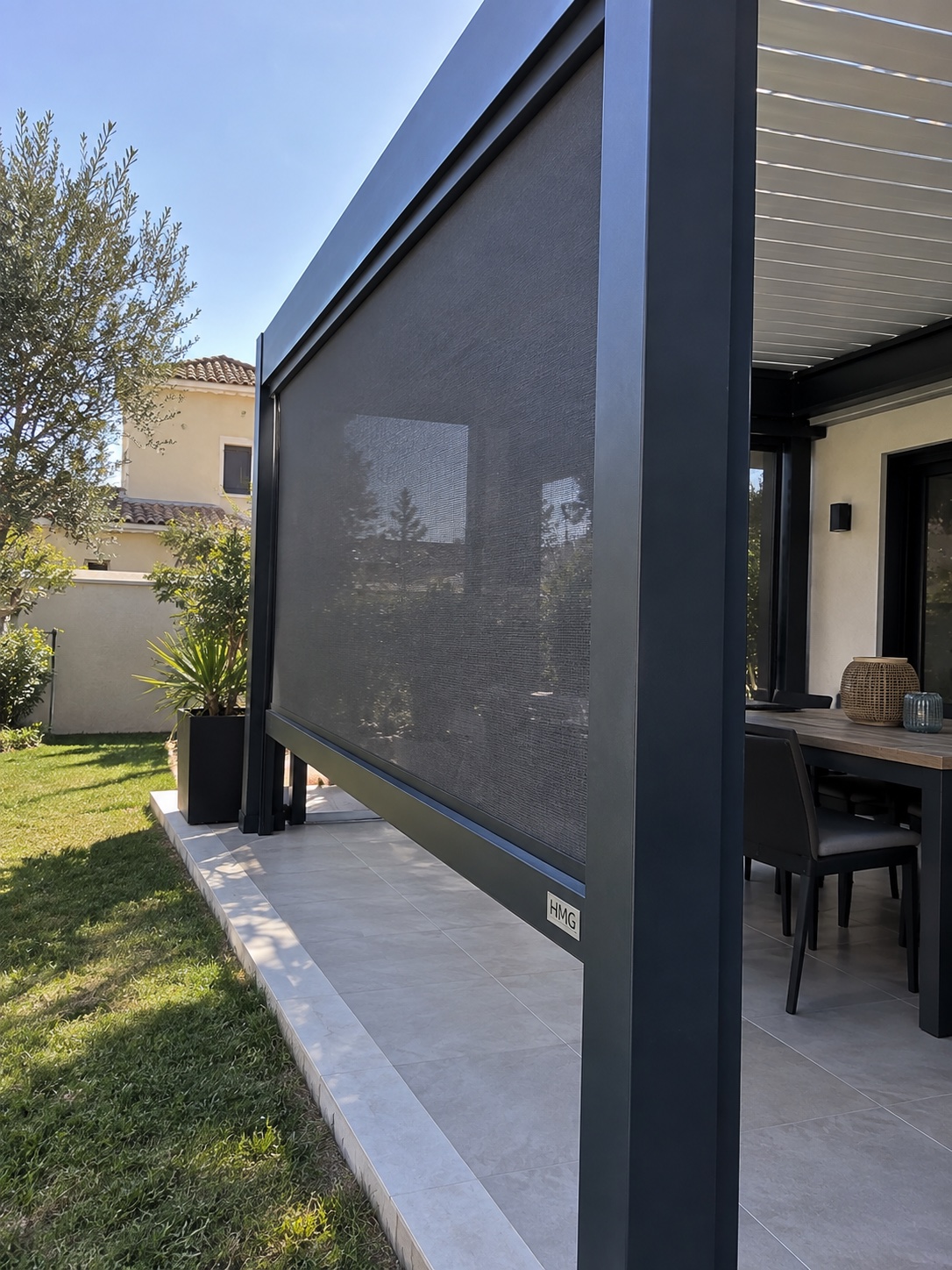 Store ZIP à toile grise abaissé entre les poteaux d’une pergola anthracite